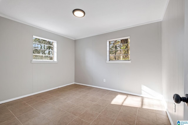 empty room with crown molding, baseboards, a wealth of natural light, and tile patterned floors