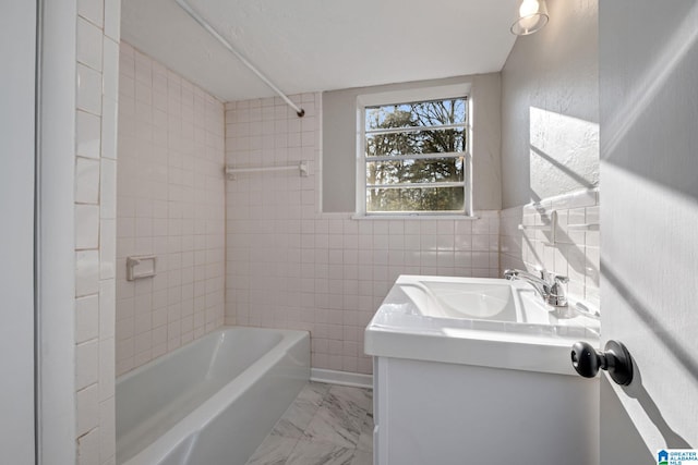 full bath featuring tile walls, marble finish floor, vanity, and shower / tub combination