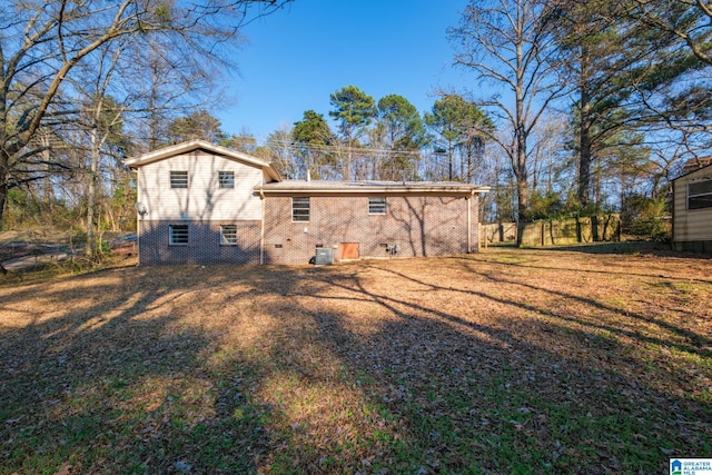 back of property featuring crawl space, a yard, and brick siding