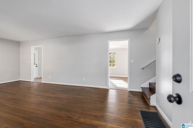 unfurnished living room with baseboards, stairway, and dark wood-style flooring