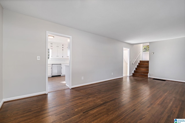 unfurnished living room with baseboards, stairs, visible vents, and dark wood-style flooring