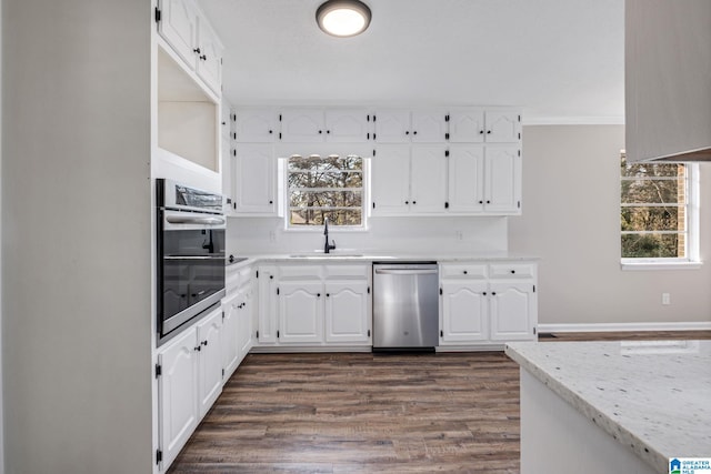 kitchen featuring stainless steel appliances, a wealth of natural light, white cabinets, and a sink