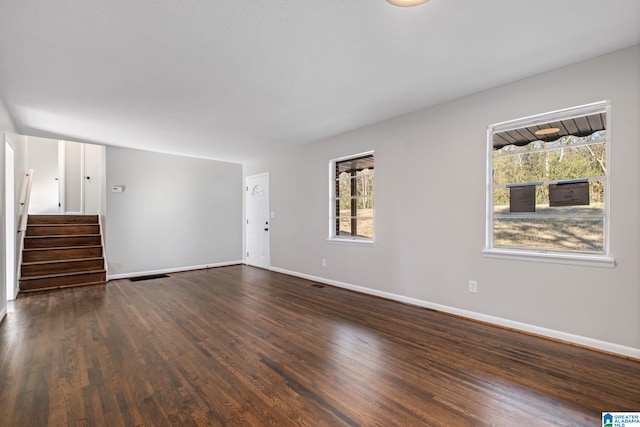 unfurnished living room featuring visible vents, stairs, baseboards, and dark wood-type flooring