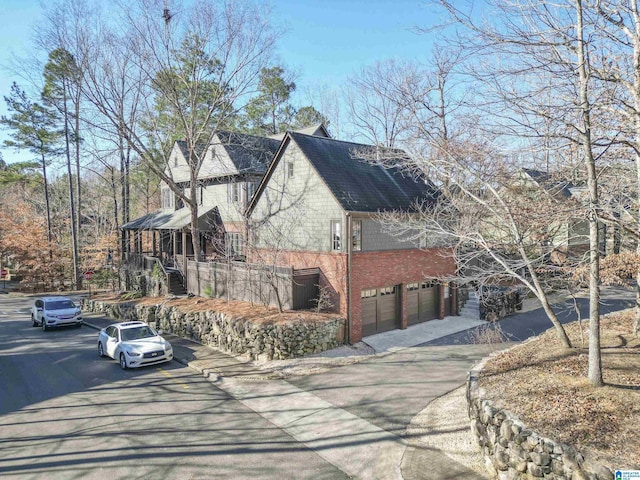 view of home's exterior with driveway, brick siding, and an attached garage