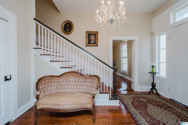 foyer with stairs, hardwood / wood-style floors, an inviting chandelier, and baseboards