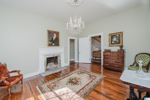 sitting room featuring a notable chandelier, a premium fireplace, baseboards, stairs, and hardwood / wood-style floors