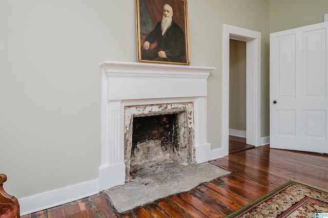 unfurnished living room with a fireplace, wood-type flooring, and baseboards