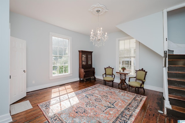 living area with hardwood / wood-style floors, stairway, an inviting chandelier, and baseboards