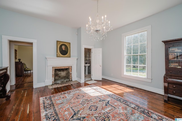 living room with a chandelier, a fireplace with flush hearth, visible vents, baseboards, and wood-type flooring