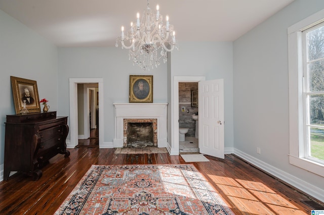 unfurnished living room featuring a fireplace with flush hearth, a chandelier, hardwood / wood-style floors, and baseboards