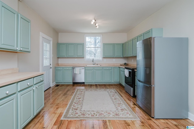 kitchen featuring light countertops, appliances with stainless steel finishes, a sink, and light wood-style flooring