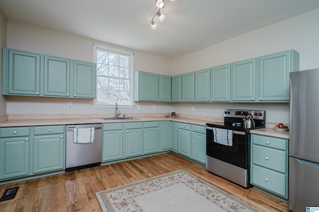 kitchen with stainless steel appliances, a sink, visible vents, light wood-style floors, and light countertops