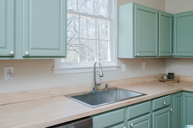 kitchen featuring light countertops, plenty of natural light, a sink, and green cabinetry