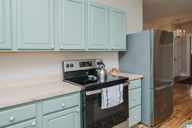 kitchen with appliances with stainless steel finishes, light countertops, light wood-style floors, and an inviting chandelier