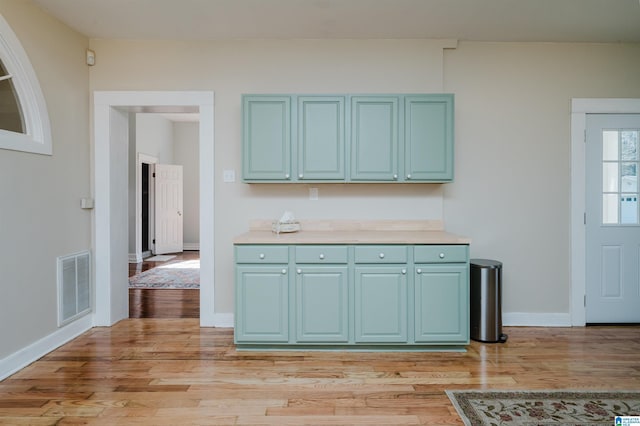 kitchen featuring light countertops, visible vents, light wood-style flooring, blue cabinets, and baseboards