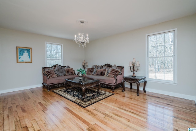 living area featuring baseboards, wood finished floors, and an inviting chandelier