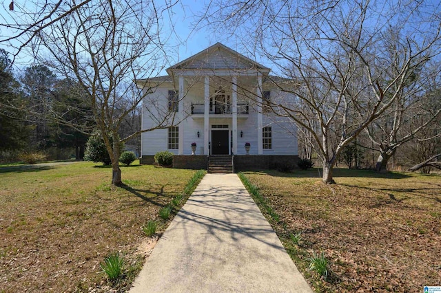 neoclassical home with a balcony and a front lawn