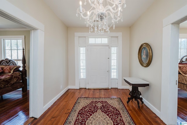 entrance foyer featuring a notable chandelier, hardwood / wood-style flooring, and baseboards