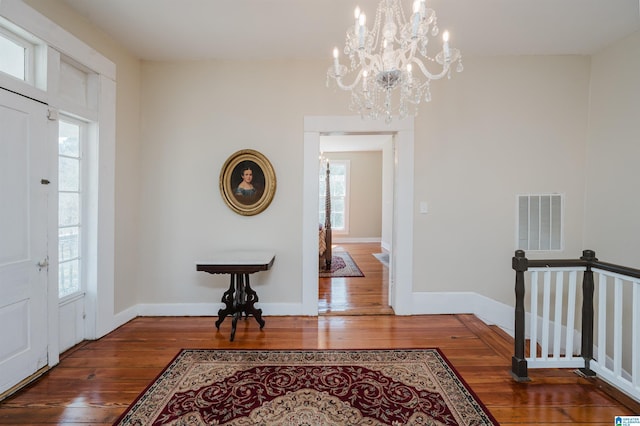 foyer featuring visible vents, a notable chandelier, baseboards, and hardwood / wood-style flooring