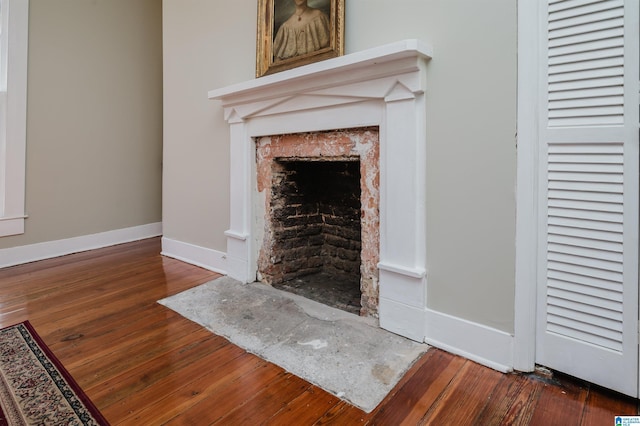 unfurnished living room with a fireplace with flush hearth, hardwood / wood-style floors, and baseboards