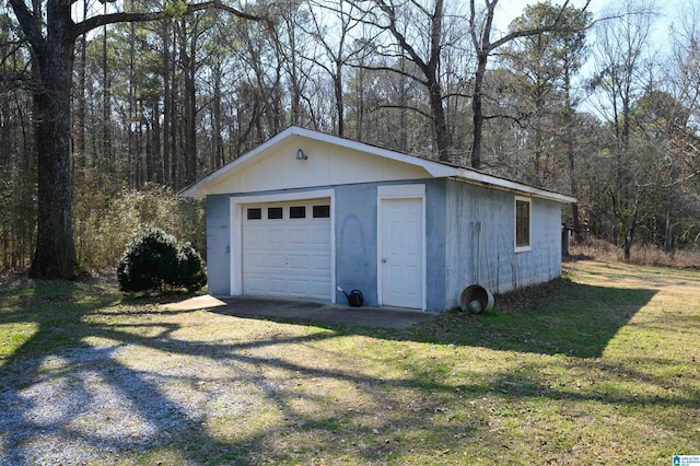 detached garage with driveway and a wooded view