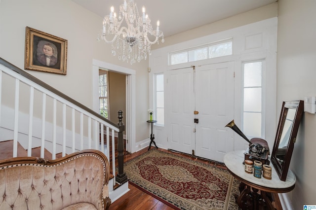 foyer entrance with an inviting chandelier, stairway, baseboards, and wood finished floors