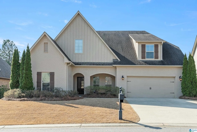 view of front facade featuring board and batten siding, roof with shingles, concrete driveway, and brick siding