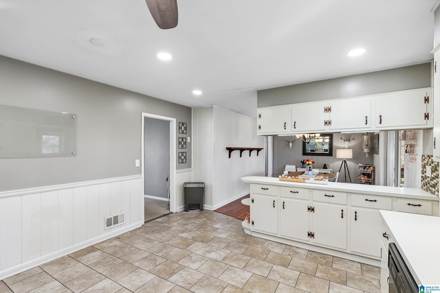 kitchen with light countertops, visible vents, white cabinets, wainscoting, and dishwasher