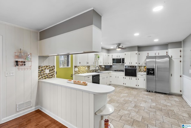 kitchen featuring a peninsula, a sink, visible vents, light countertops, and black appliances