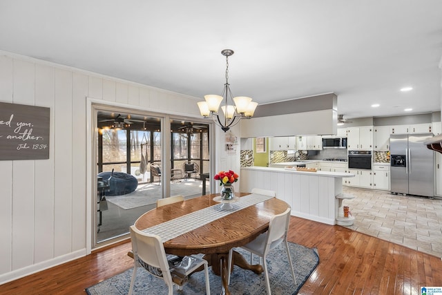 dining area with ornamental molding, light wood-style flooring, and ceiling fan with notable chandelier