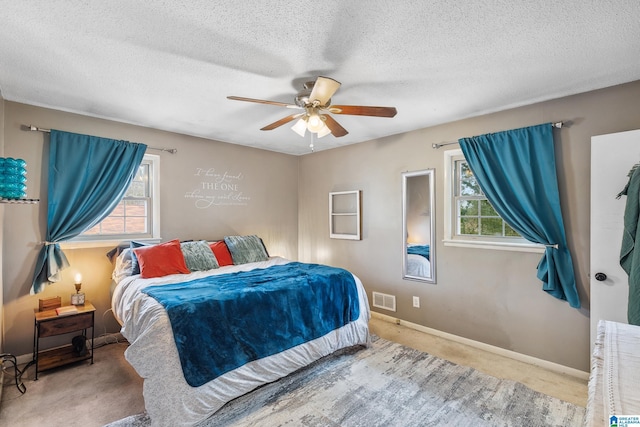 carpeted bedroom with baseboards, multiple windows, visible vents, and a textured ceiling