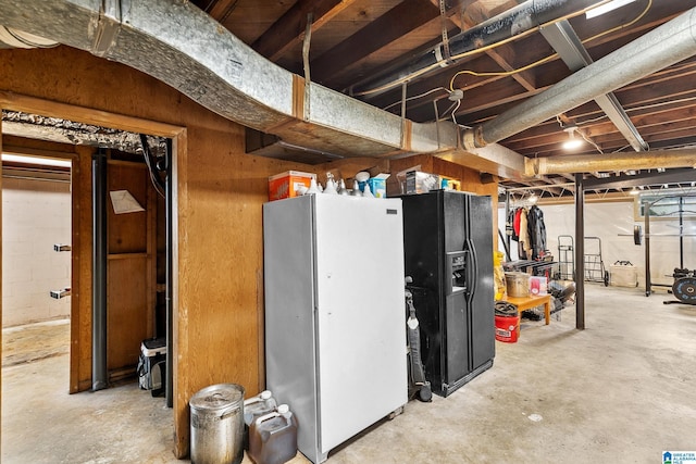 unfinished below grade area featuring black refrigerator with ice dispenser and freestanding refrigerator