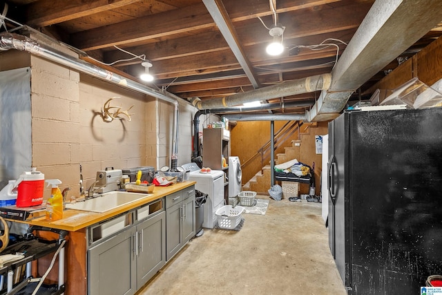 unfinished basement featuring freestanding refrigerator, stairway, a sink, and washing machine and clothes dryer