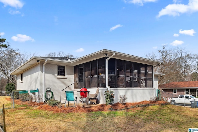 exterior space with brick siding, fence, a sunroom, a gate, and a front lawn