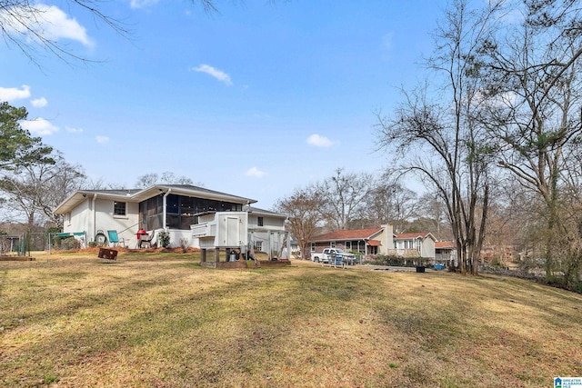 rear view of property with a sunroom, a lawn, and fence