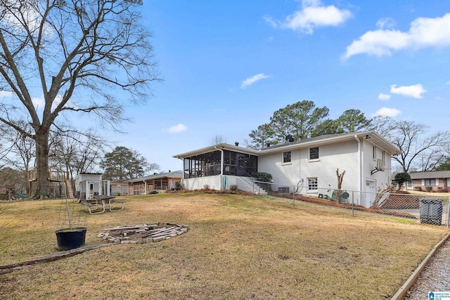 rear view of property with a sunroom, fence, a lawn, and stucco siding