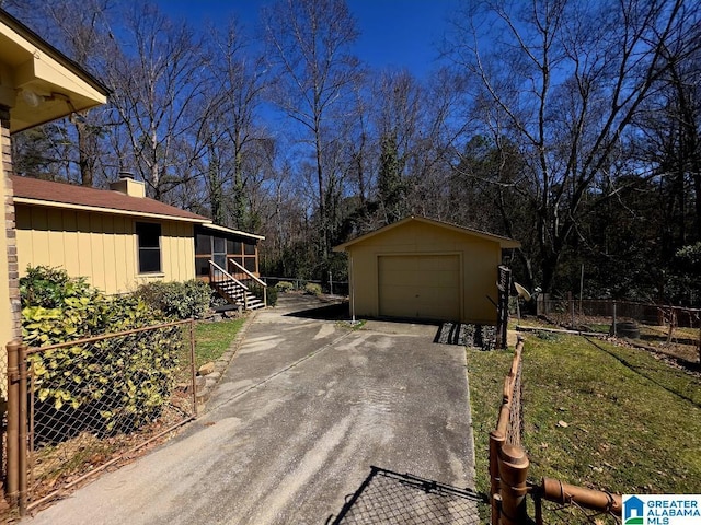 view of side of home featuring an outbuilding, a detached garage, a chimney, fence, and driveway