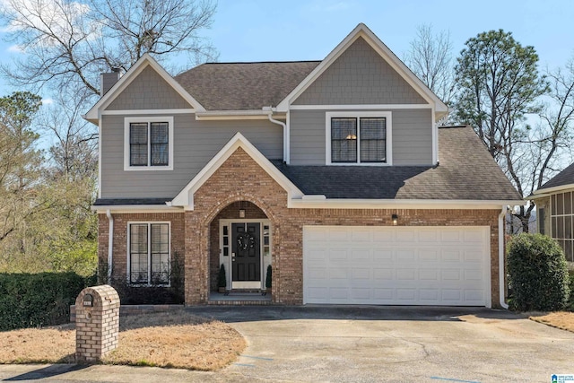 craftsman-style house featuring driveway, a shingled roof, and brick siding