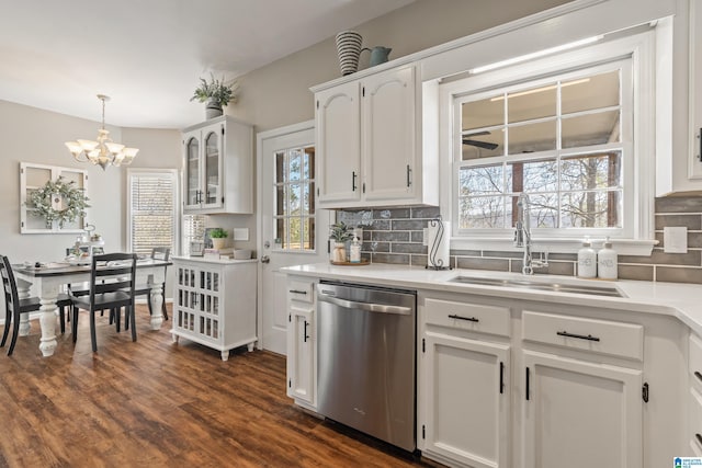 kitchen featuring tasteful backsplash, stainless steel dishwasher, dark wood-type flooring, white cabinets, and a sink