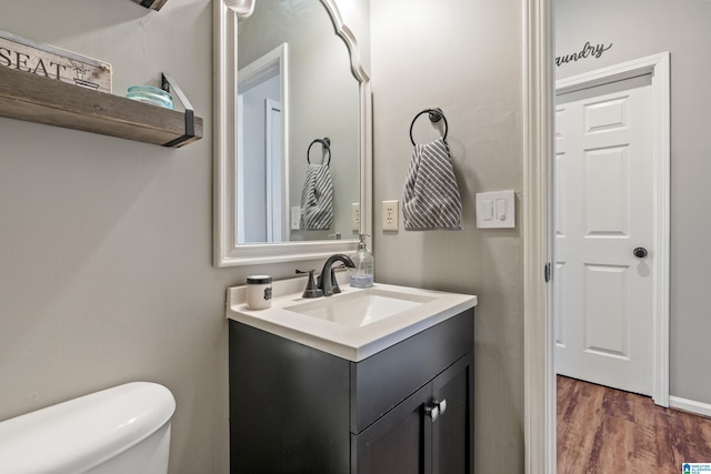 bathroom featuring toilet, wood finished floors, and vanity