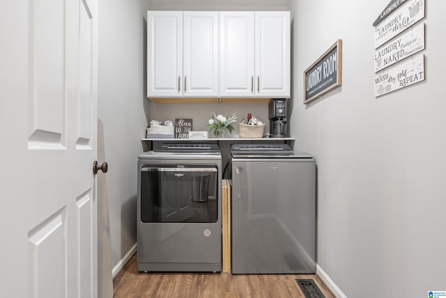 clothes washing area with cabinet space, baseboards, wood finished floors, and washing machine and clothes dryer