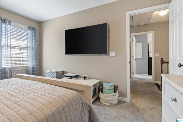 bedroom with light carpet, attic access, and baseboards