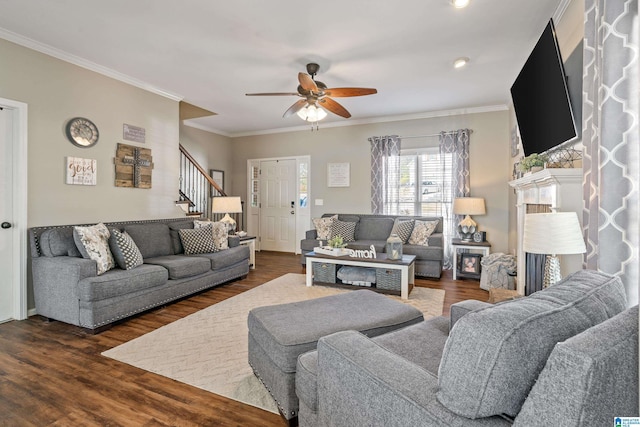 living area featuring a fireplace, dark wood finished floors, stairway, ornamental molding, and ceiling fan