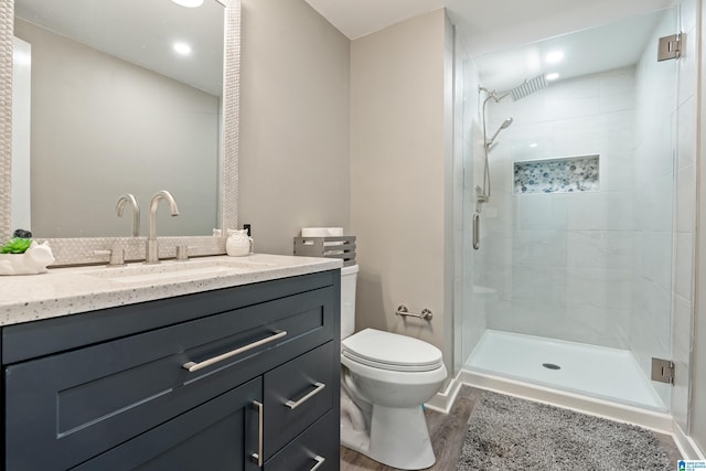 full bathroom featuring toilet, a stall shower, wood finished floors, and vanity