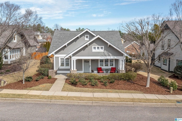 view of front of house featuring a porch, roof with shingles, and fence