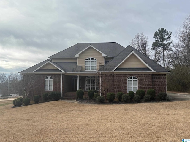 view of front of property with a front lawn, a porch, and brick siding