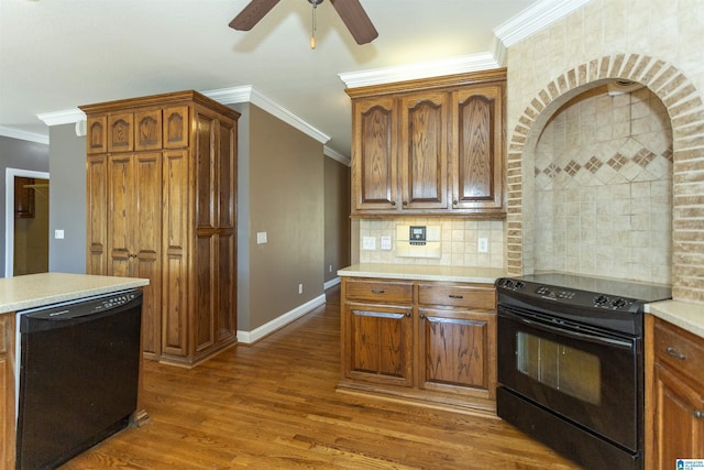 kitchen with wood finished floors, black appliances, light countertops, and ornamental molding