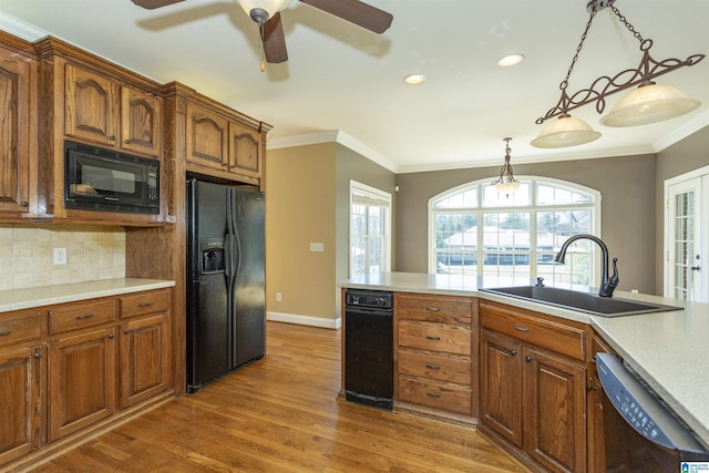 kitchen featuring black appliances, wood finished floors, crown molding, and a sink