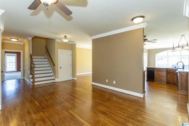 unfurnished living room with stairway, wood finished floors, and ornamental molding