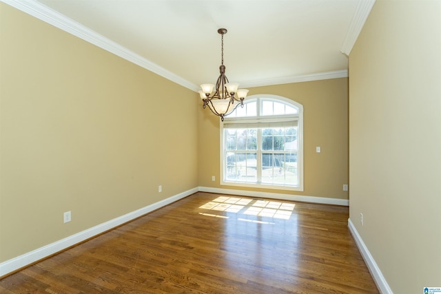 spare room with baseboards, an inviting chandelier, wood finished floors, and crown molding